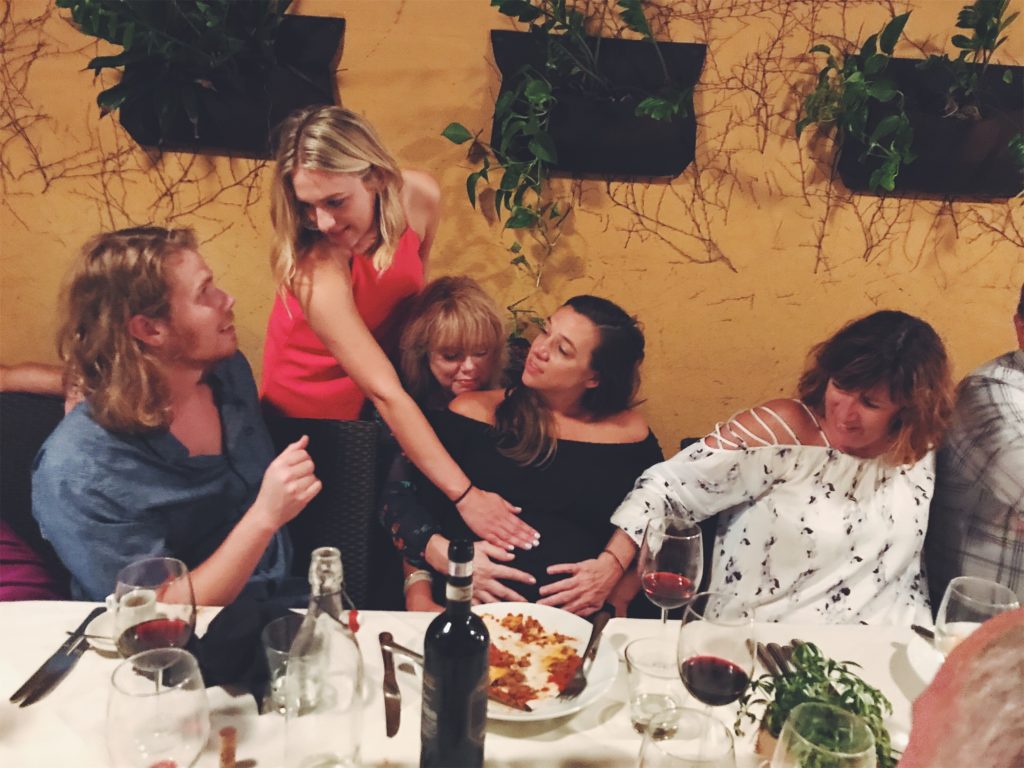 Photo of family feeling bride's baby bump at wedding rehearsal dinner shot with iPhone 7 Plus