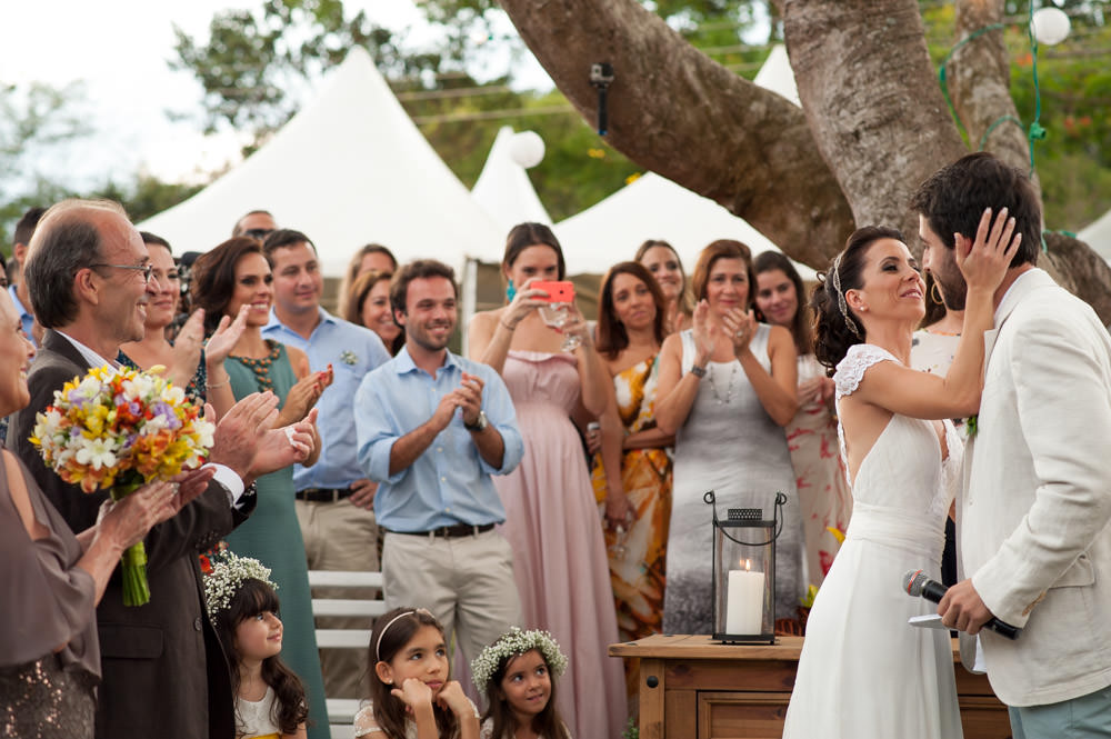 Wedding photography image of bride putting her hand on the groom's cheek while the attendees applaud