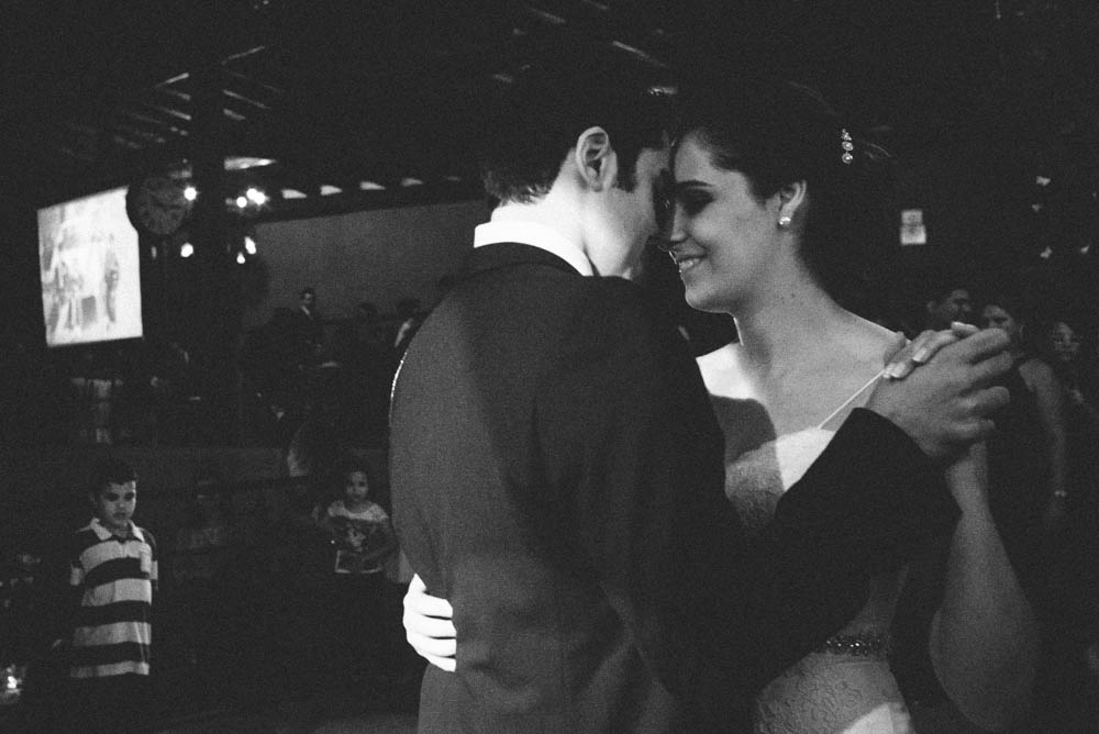 Black and white wedding photography image of a bride and groom doing their first dance and smiling at each other