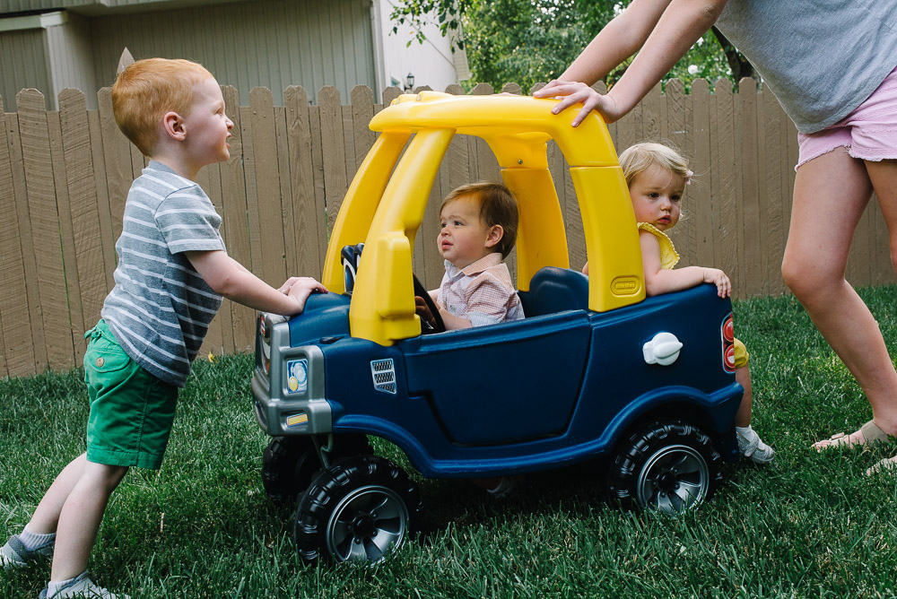 image of kids at a one year old birthday party being pushed around in a toy car