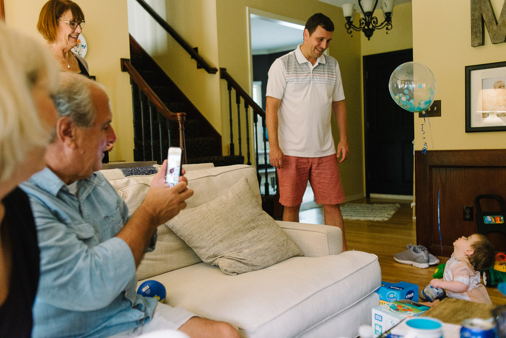 image of a one year old's family laughing as he opens gifts