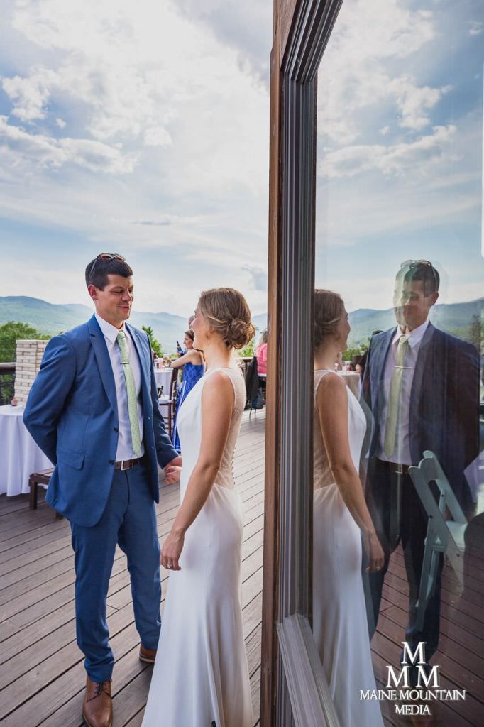 Picture of a bride and groom looking at each other outside in the sun after their ceremony as their reception is about to start and being reflected in a window