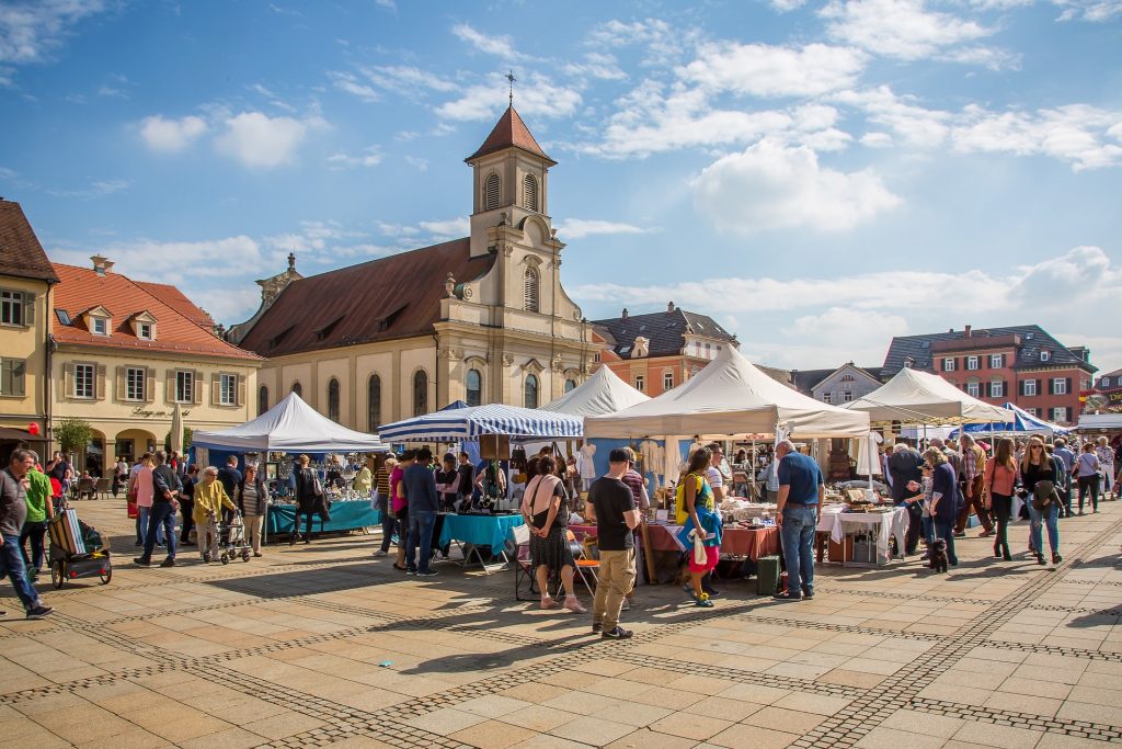 Image of an outdoor market with the sun shining and a bright blue sky with a few clouds, serving as an example as to finding marketplaces to sell your landscape photography