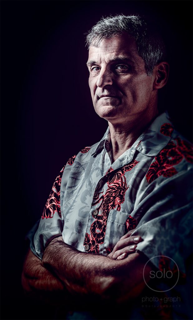 Portrait of a man with a blue button down short sleeve shirt lit with creative portrait rembrandt lighting