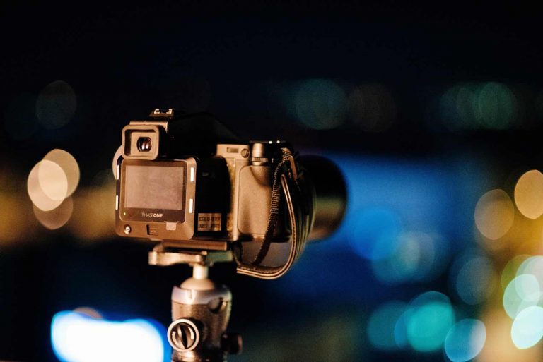 A PhaseOne camera set up on a tripod in a dark setting.