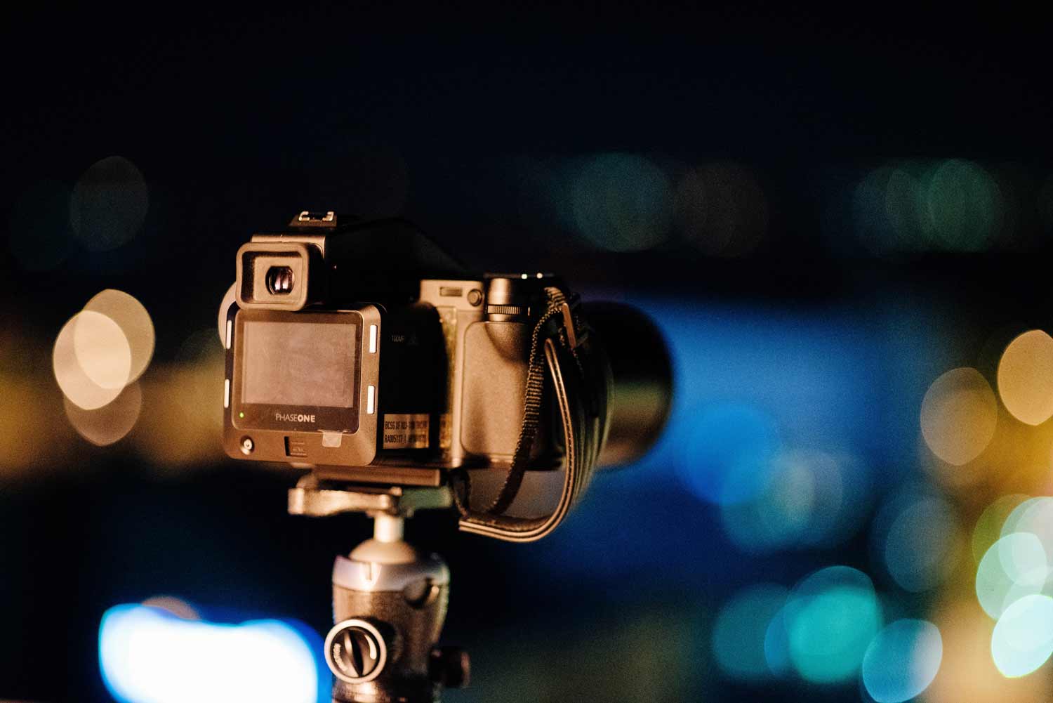 A PhaseOne camera set up on a tripod in a dark setting.