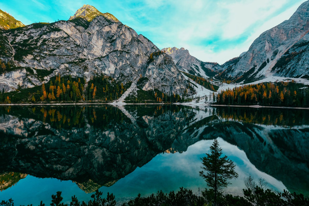 HDR photo of a lake, pine trees, and a blue sky with white puffy clouds