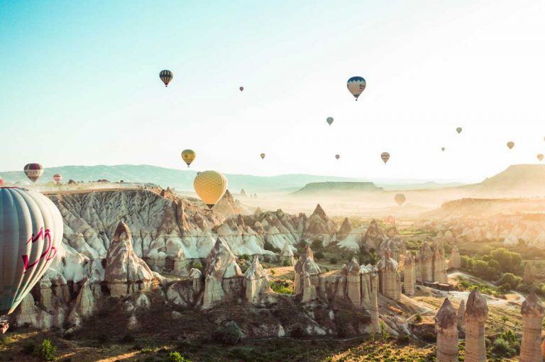 Hot air balloons above a canyon with rock formations.