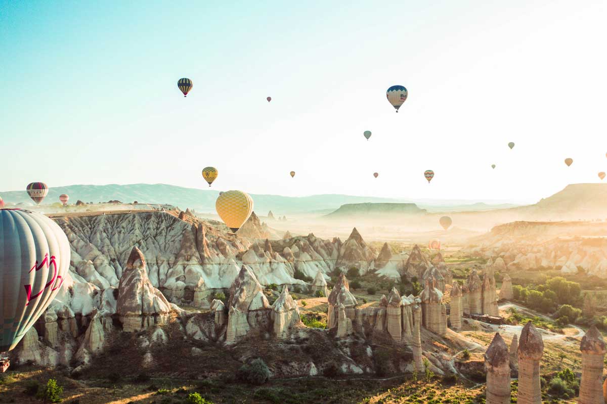 Hot air balloons above a canyon with rock formations.