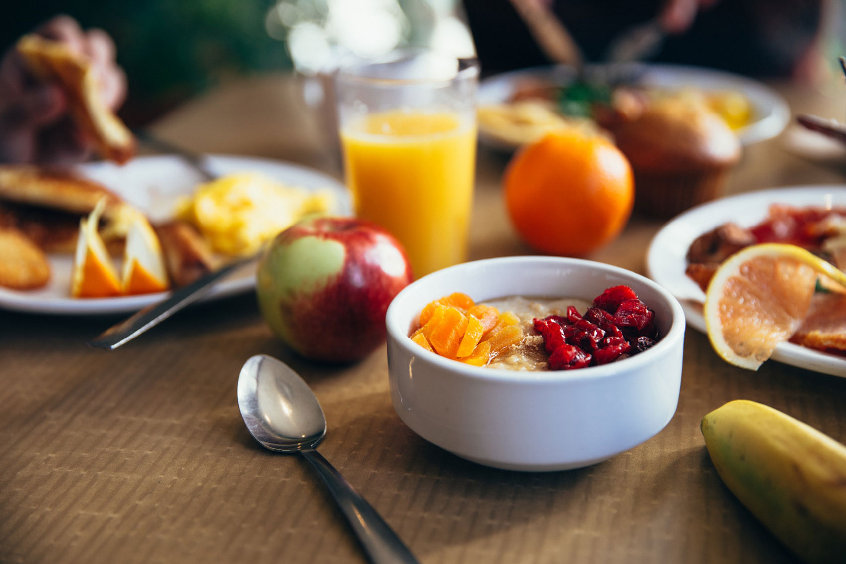 Breakfast food and orange juice laid out on a table.