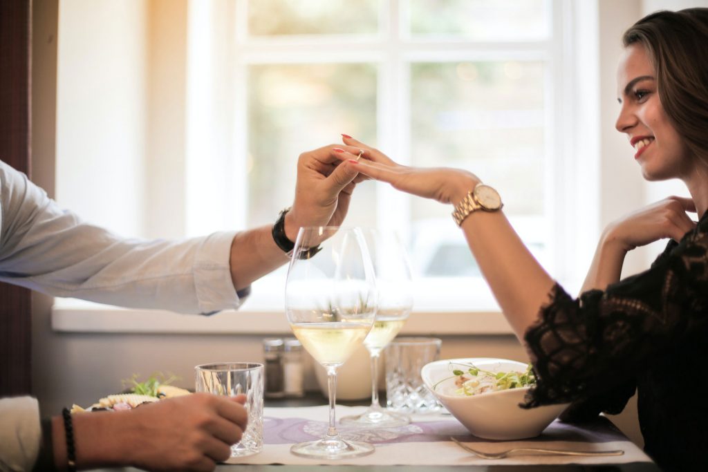 Image of a man putting a ring on a woman's finger after asking her to marry him