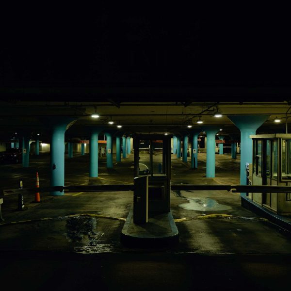 A parking garage at night with light blue columns.