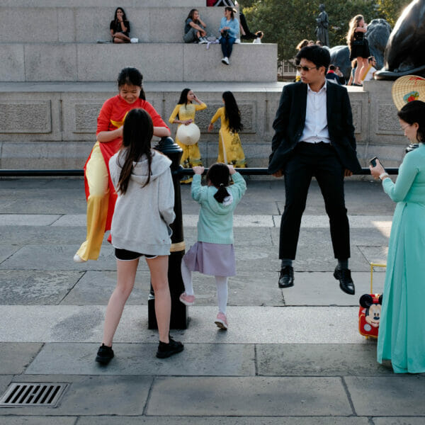 A family with luggage sitting on a handrail.