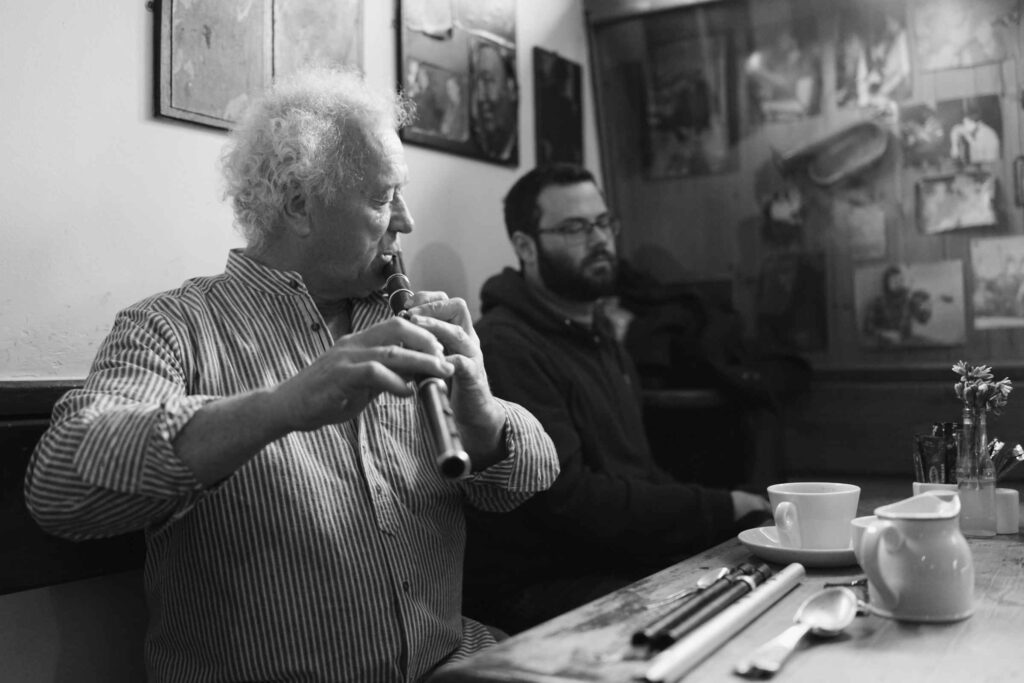 A man playing a flute while sitting at a table.