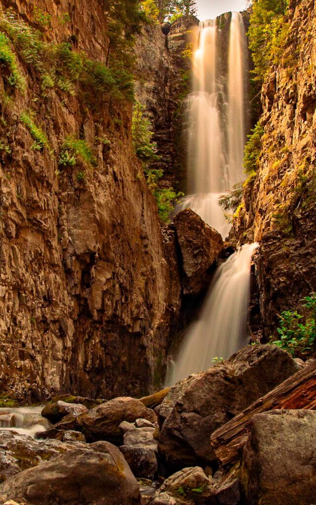 A tall waterfall with green vegetation.